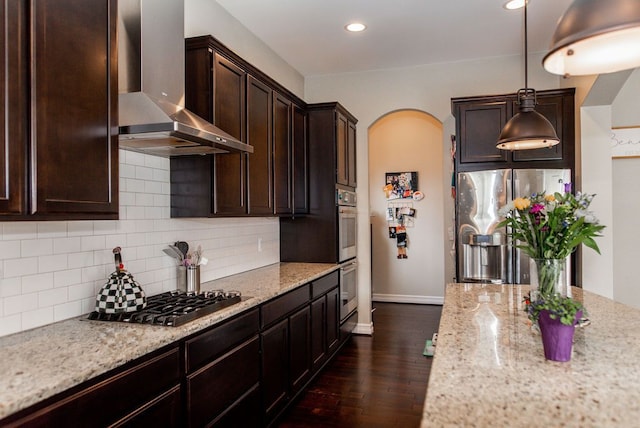 220 S Castell Ave, Rochester, MI 48307 - kitchen featuring wall chimney range hood, stainless steel appliances, dark brown cabinets, arched walkways, and backsplash