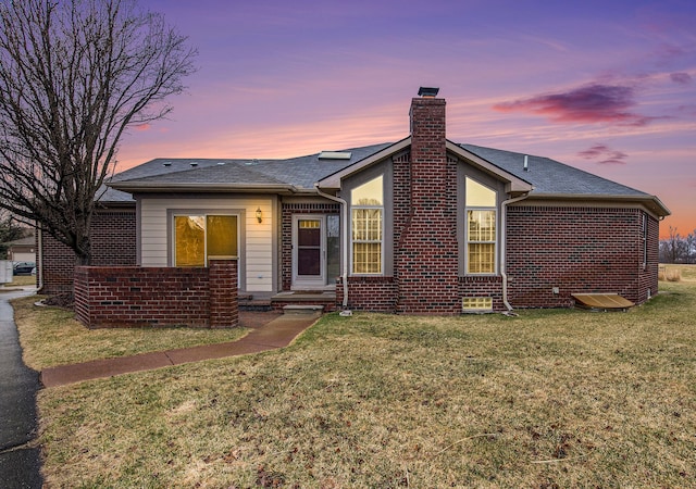 50128 Bethesda, Shelby Twp, MI 48317 - back of house at dusk with a chimney, brick siding, and a yard