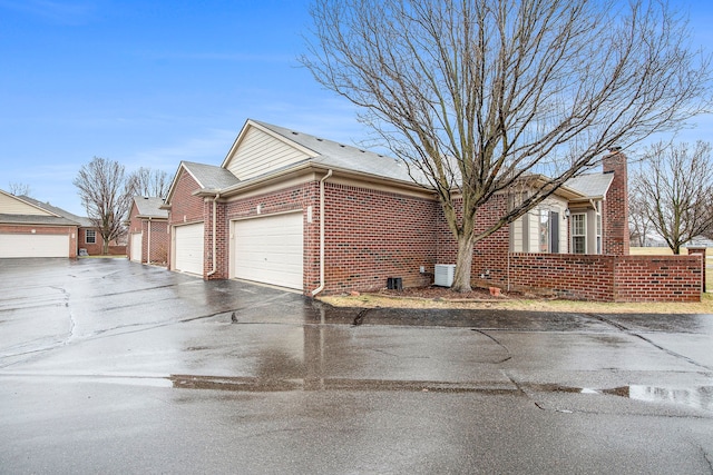 50128 Bethesda, Shelby Twp, MI 48317 - view of side of property with a chimney, brick siding, aphalt driveway, and an attached garage
