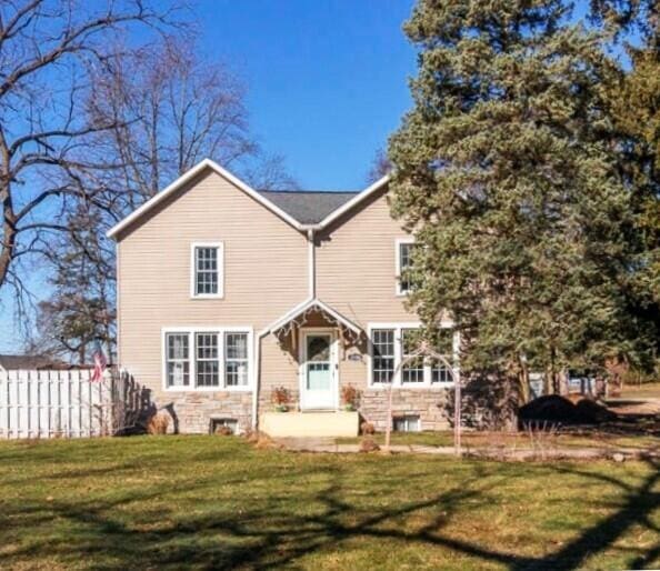 rear view of property featuring a lawn and fence