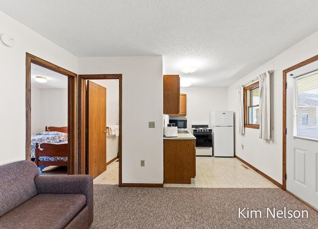 6195 Murray Rd, Whitehall, MI 49461 - kitchen featuring light carpet, a textured ceiling, freestanding refrigerator, black microwave, and stove