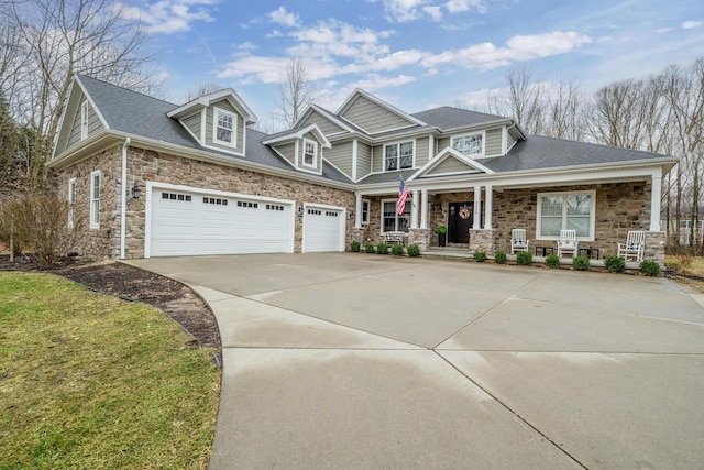 craftsman-style house with a porch, concrete driveway, stone siding, and roof with shingles