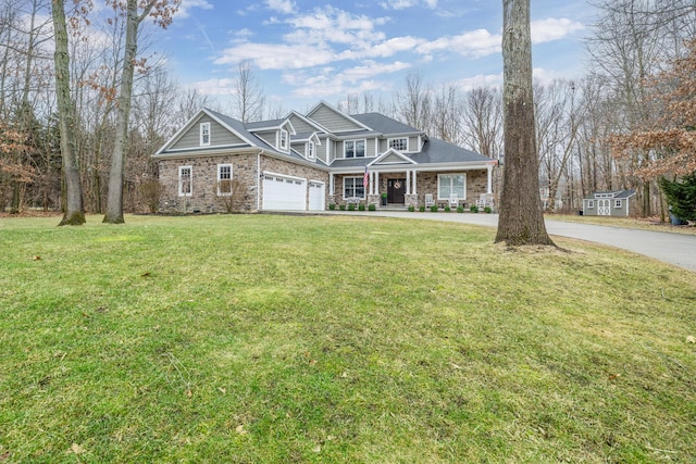view of front of home with a porch, stone siding, driveway, and a front lawn