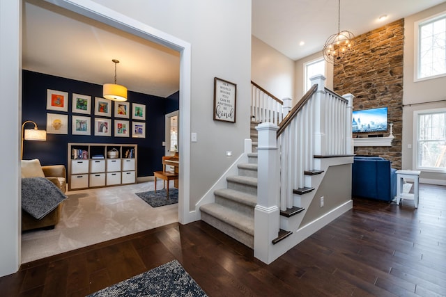 foyer entrance with baseboards, an inviting chandelier, stairs, a towering ceiling, and wood-type flooring
