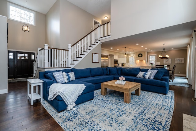 living area with dark wood-style floors, a chandelier, stairway, and baseboards
