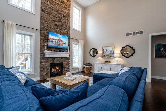 living area featuring visible vents, baseboards, dark wood-type flooring, and a fireplace