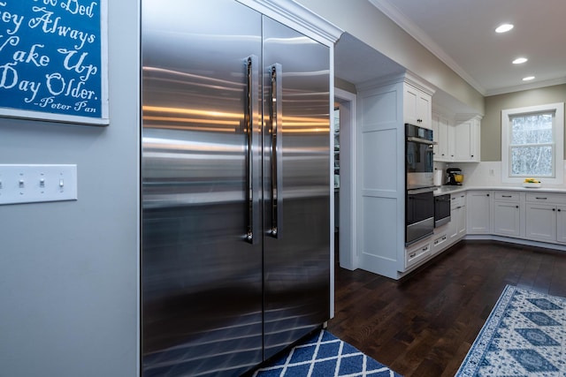 kitchen with ornamental molding, recessed lighting, appliances with stainless steel finishes, white cabinets, and dark wood-style flooring