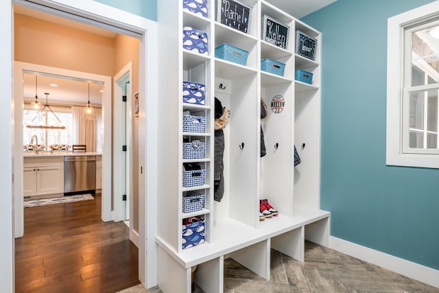mudroom with a notable chandelier, wood finished floors, baseboards, and a sink