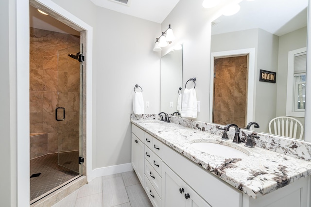 bathroom with a sink, baseboards, double vanity, and a shower stall