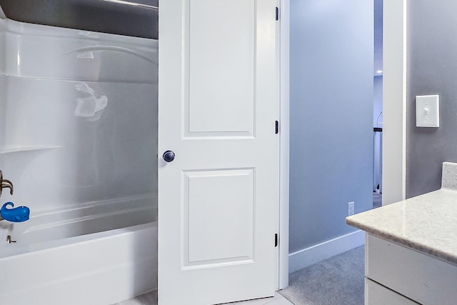 bathroom featuring vanity, tub / shower combination, and baseboards