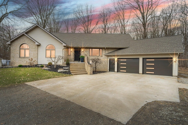 view of front of home with concrete driveway, an attached garage, a shingled roof, and a front yard