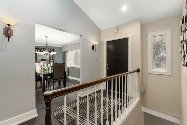 hall with an upstairs landing, baseboards, and a notable chandelier