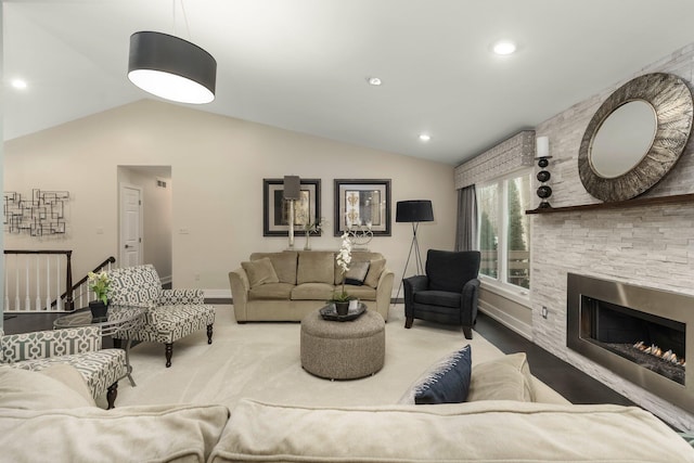 living area featuring baseboards, a stone fireplace, recessed lighting, and vaulted ceiling