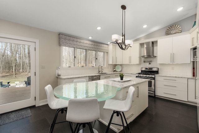 kitchen featuring recessed lighting, a center island, a sink, wall chimney range hood, and stainless steel appliances