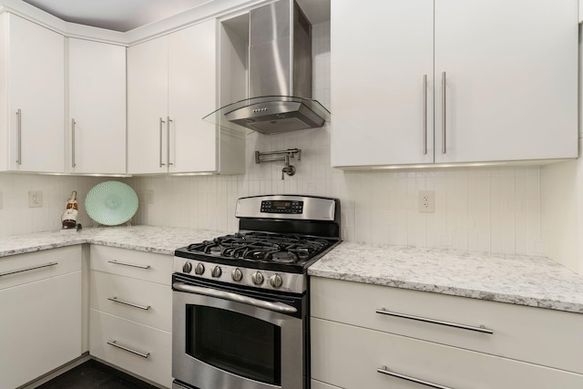 kitchen featuring wall chimney range hood, white cabinets, decorative backsplash, and gas range