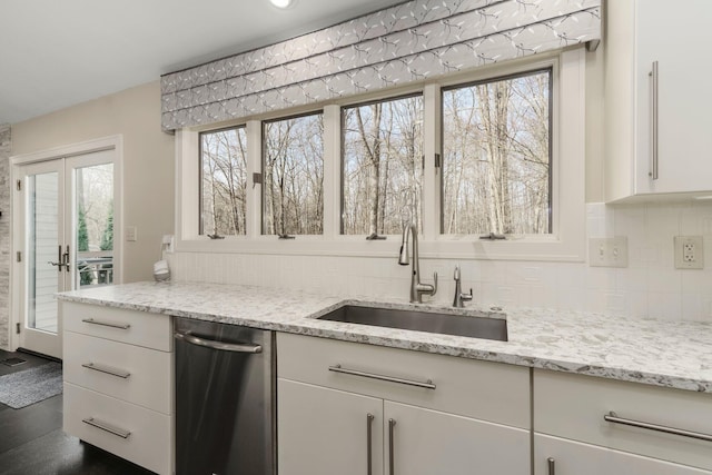 kitchen featuring a wealth of natural light, tasteful backsplash, a sink, and white cabinets