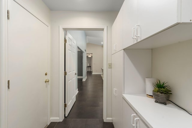 corridor with baseboards and dark tile patterned flooring
