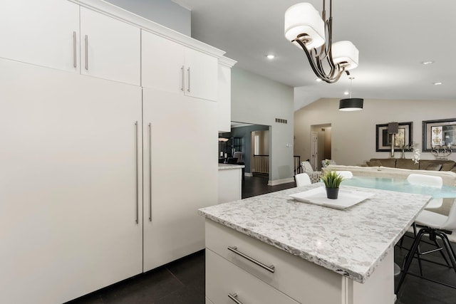 kitchen featuring light stone counters, vaulted ceiling, pendant lighting, white cabinetry, and open floor plan