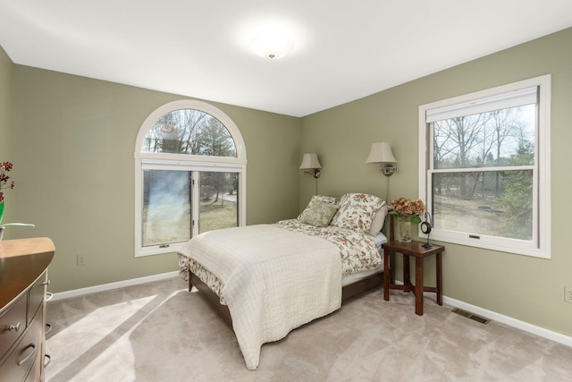 bedroom with baseboards, visible vents, and light colored carpet