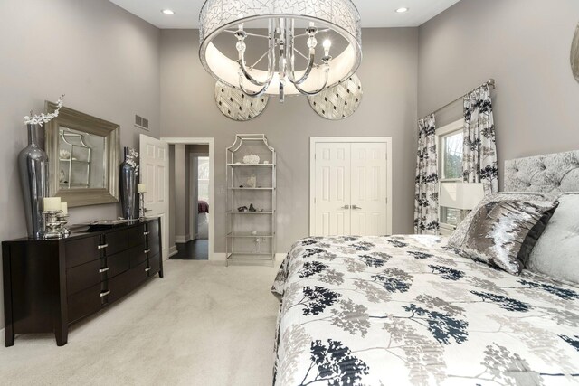 bedroom featuring light carpet, a chandelier, visible vents, and a high ceiling
