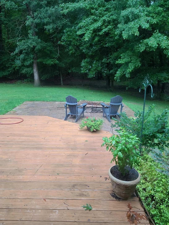 wooden terrace featuring a fire pit and a lawn