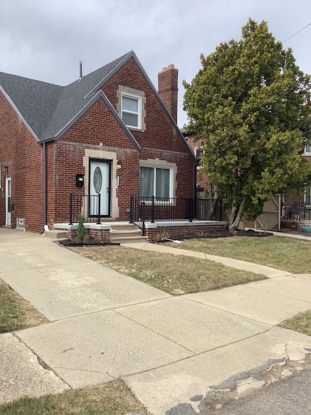 view of front of home featuring brick siding, roof with shingles, and a chimney