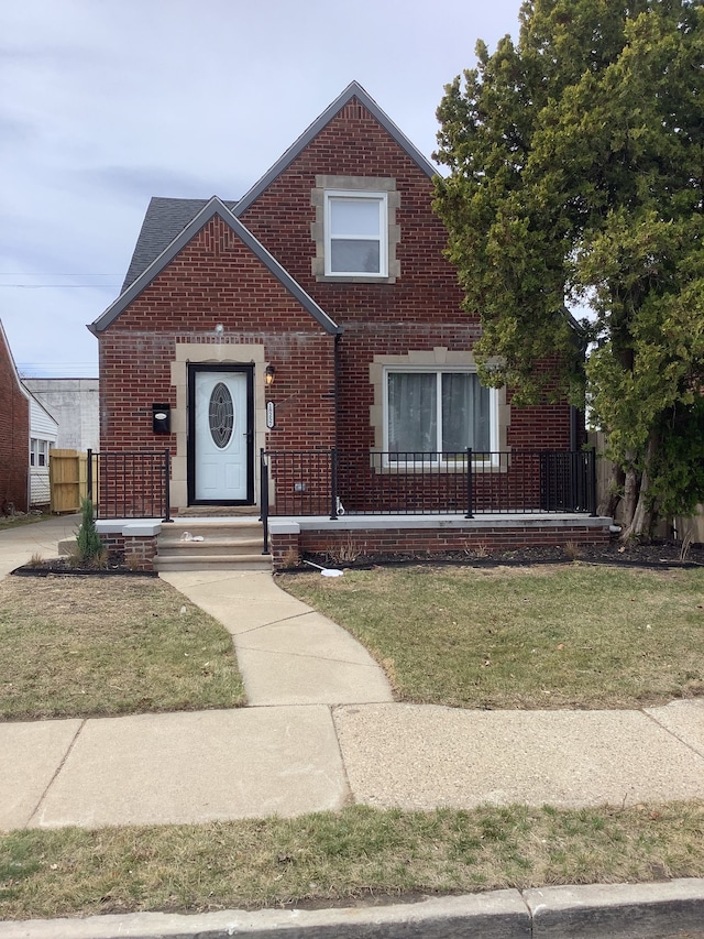 view of front of house featuring brick siding, a front yard, and fence