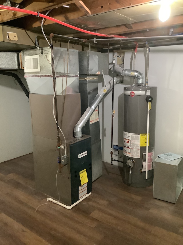 utility room with gas water heater, heating unit, and visible vents