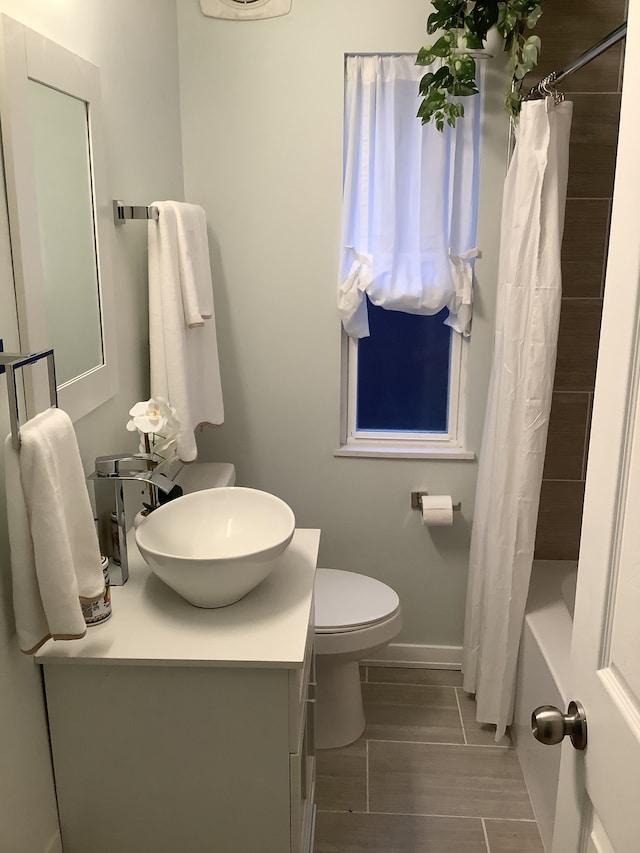 full bathroom featuring toilet, vanity, baseboards, and shower / bathtub combination with curtain