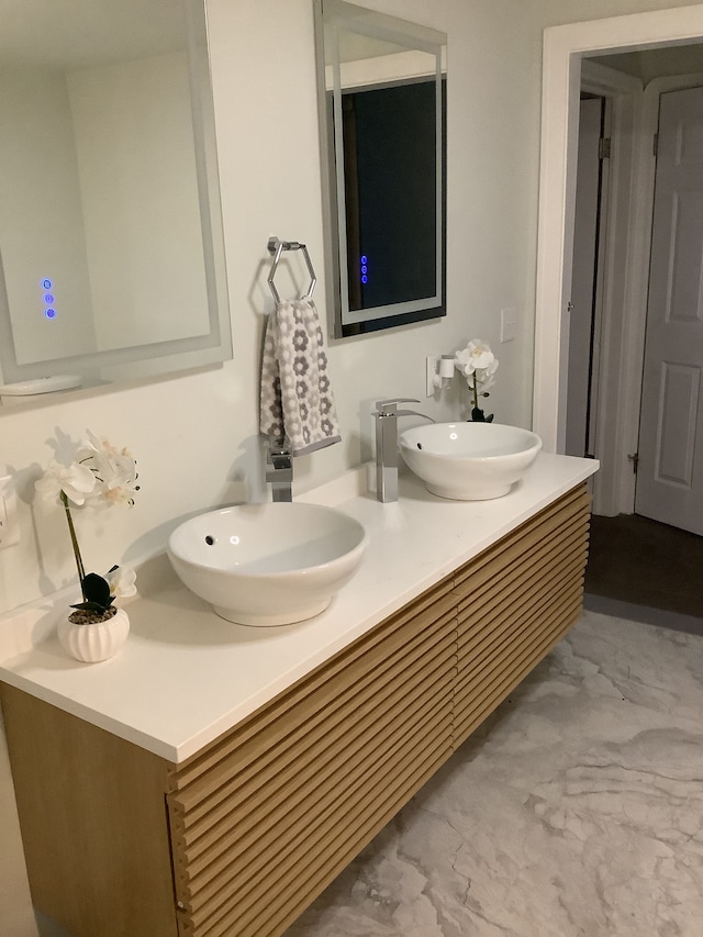 bathroom with double vanity, marble finish floor, and a sink