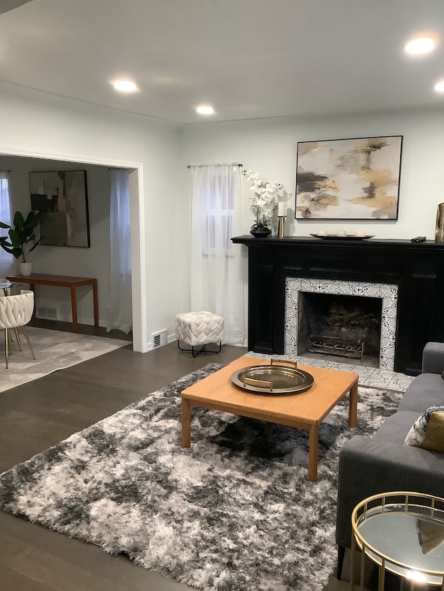 living area with a tiled fireplace, visible vents, recessed lighting, and wood finished floors