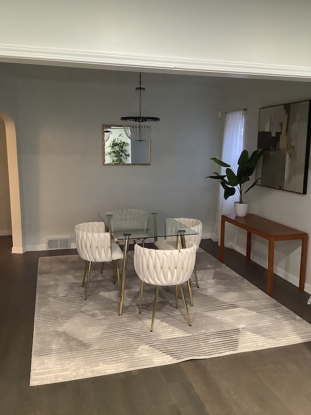 dining room featuring visible vents, baseboards, an inviting chandelier, wood finished floors, and arched walkways