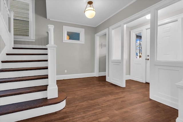 foyer entrance with stairway, baseboards, ornamental molding, and dark wood finished floors