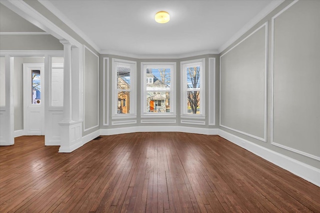 spare room with decorative columns, a healthy amount of sunlight, and a decorative wall