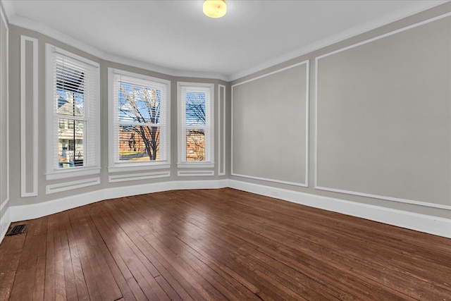 spare room featuring a decorative wall, a healthy amount of sunlight, and wood-type flooring
