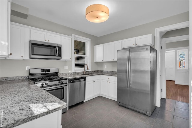 kitchen featuring a sink, stainless steel appliances, light stone countertops, and white cabinetry