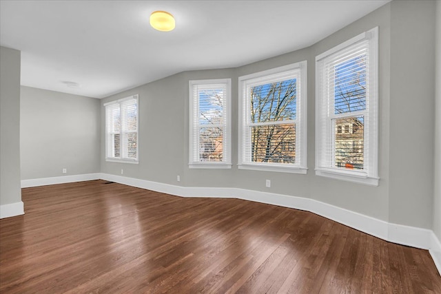 empty room with baseboards and dark wood-type flooring