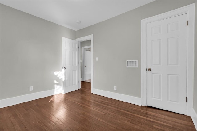 unfurnished bedroom featuring baseboards, visible vents, and wood-type flooring