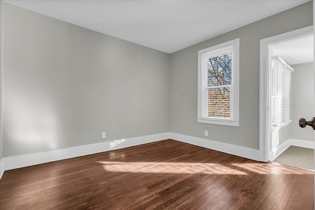 spare room with dark wood finished floors and baseboards