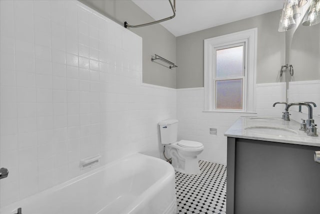 bathroom featuring vanity, tile patterned flooring, wainscoting, tile walls, and toilet