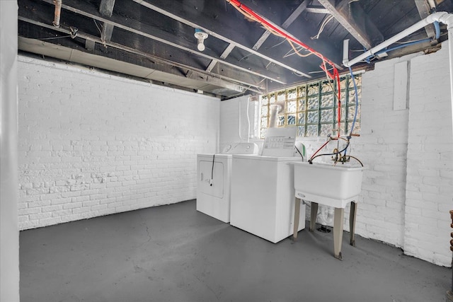 basement with brick wall and washer and clothes dryer