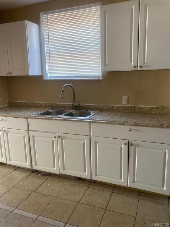 kitchen featuring a sink, white cabinetry, and light tile patterned floors
