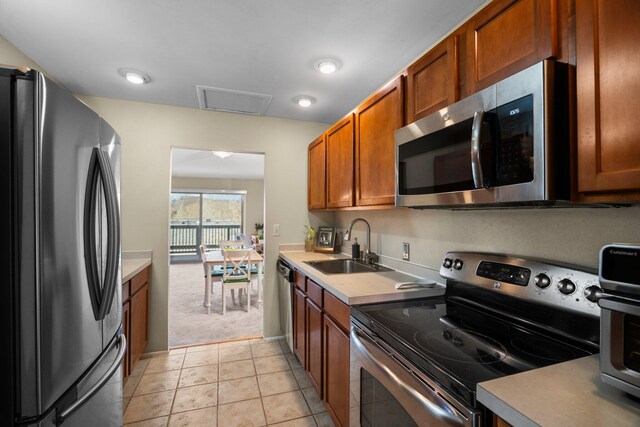 kitchen with a sink, light countertops, brown cabinetry, and stainless steel appliances