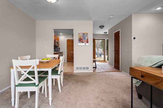 dining area featuring light carpet, visible vents, and baseboards