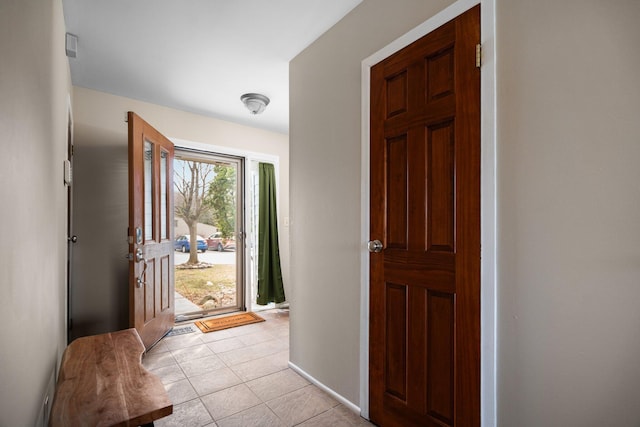 foyer featuring light tile patterned flooring and baseboards