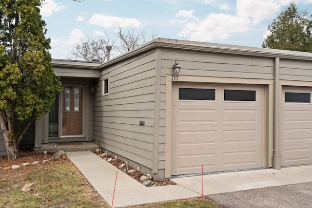 doorway to property with aphalt driveway and an attached garage