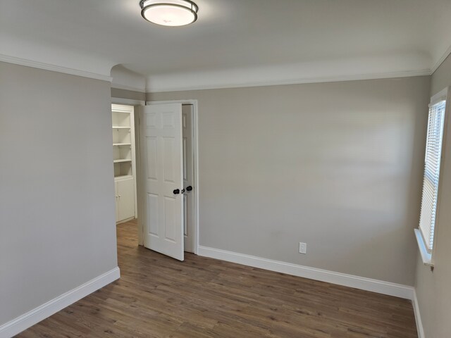 spare room with baseboards, wood finished floors, plenty of natural light, and crown molding