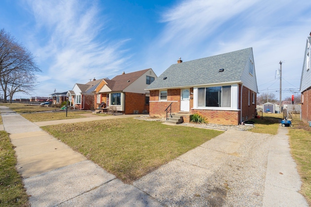 bungalow-style house featuring a chimney, brick siding, a shingled roof, and a front yard