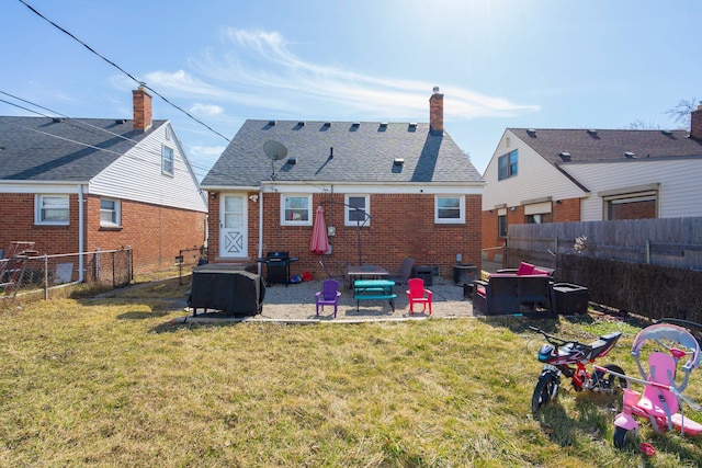 back of property featuring a fenced backyard, a yard, a patio area, and brick siding