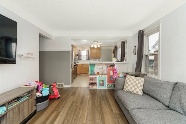 living area with a ceiling fan, light wood-style flooring, visible vents, and plenty of natural light